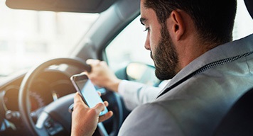 Man-driving-car-checking-phone-safety-concerns
