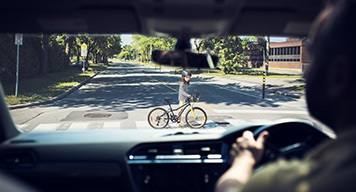 Man-Driving-Car-Watching-Kids-Crossing-Road-Bike