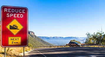 red-reduce-speed-sign-blue-mountain-traffic-safety