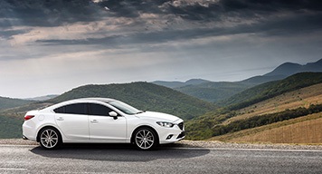 white-sedan-parking-hill-mountain-view