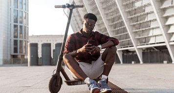 Person sitting on parked eScooter in a city setting