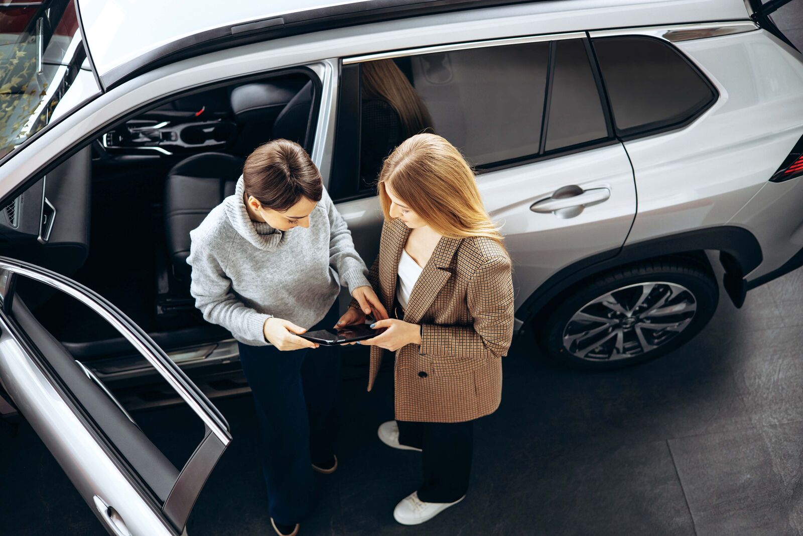 two women standing next to car