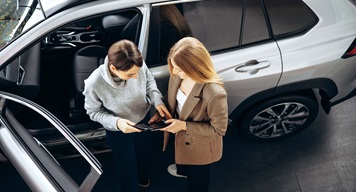two women standing next to car