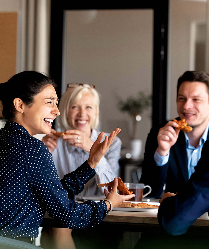 Group-Of-People-Sitting-At-A-Table-Eating-And-Laughing
