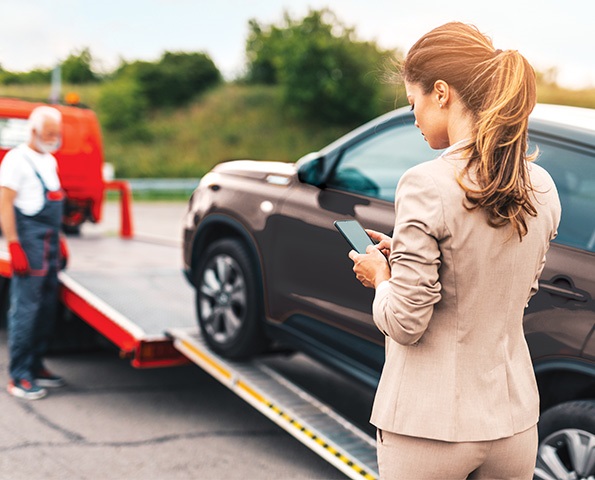 woman-getting-car-towed-on-phone woman-getting-car-towed-looking-at-mobile-phone