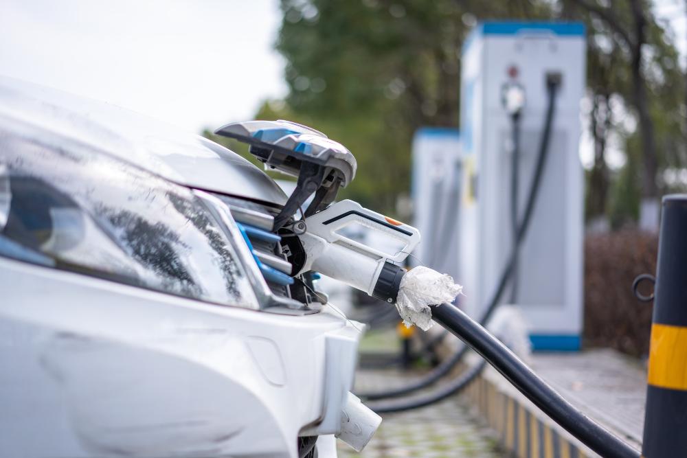 Does salary sacrifice remove the need to submit a P11D: A close-up of a white electric car plugged in and charging at a row of public charging points, with the charging cable connected to the front of the vehicle.