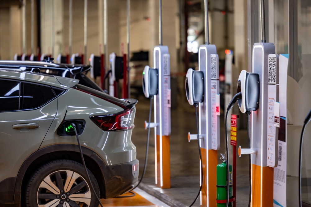 EV Charging costs: An electric vehicle plugged into a row of charging stations inside a car park.