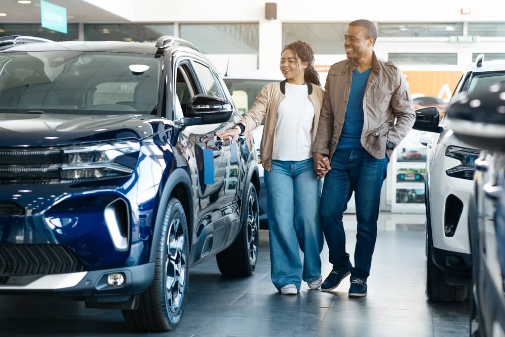 Happy couple viewing a former lease vehicle in a showroom, highlighting car value and strong car service history.