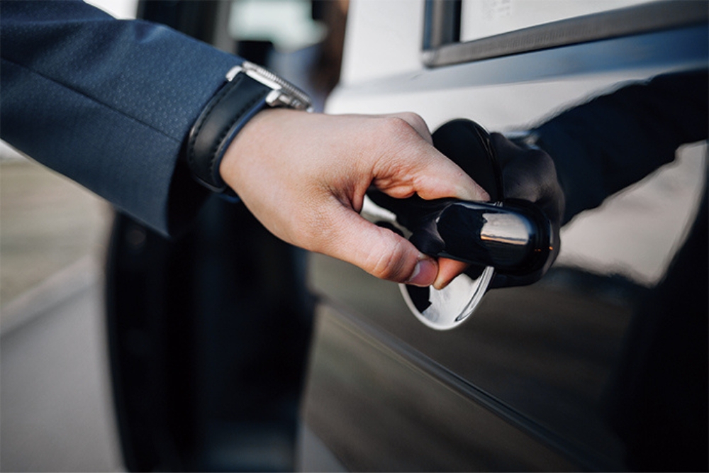 Close-up of a person opening the door of a black car, reflecting access to a lease vehicle for business or personal use.