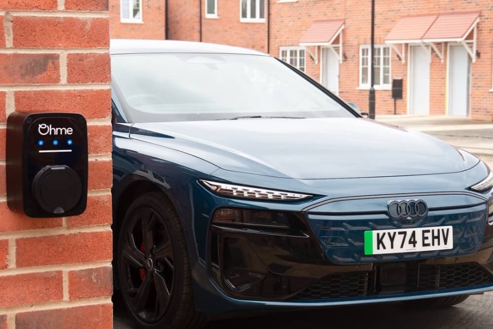 Ohme EV home charger installed on a residential wall beside a car, highlighting the role of EV home charging in a salary sacrifice car scheme and employee car benefits.