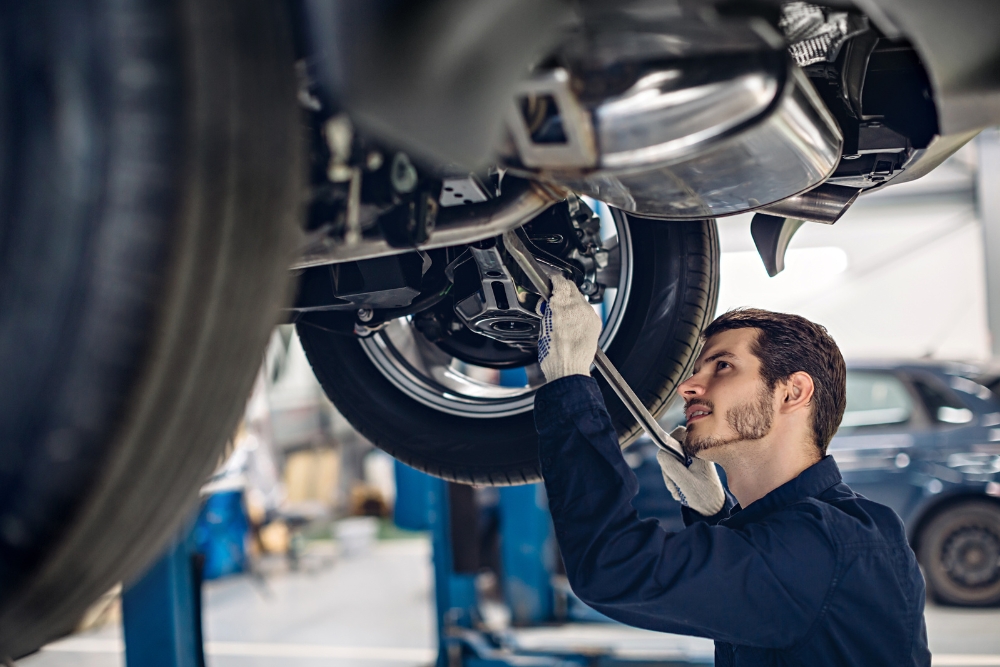 Preventative Fleet Maintenance: A technician inspecting the underside of a vehicle on a lift.